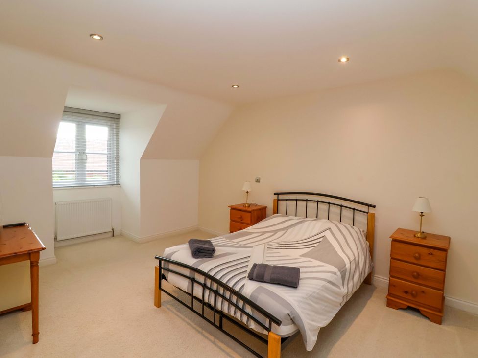 A bedroom featuring a bed, bedside tables, and a window at The Mill House in Glastonbury