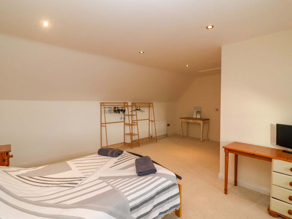 A bedroom with a bed and a clothes rack at The Mill House in Glastonbury