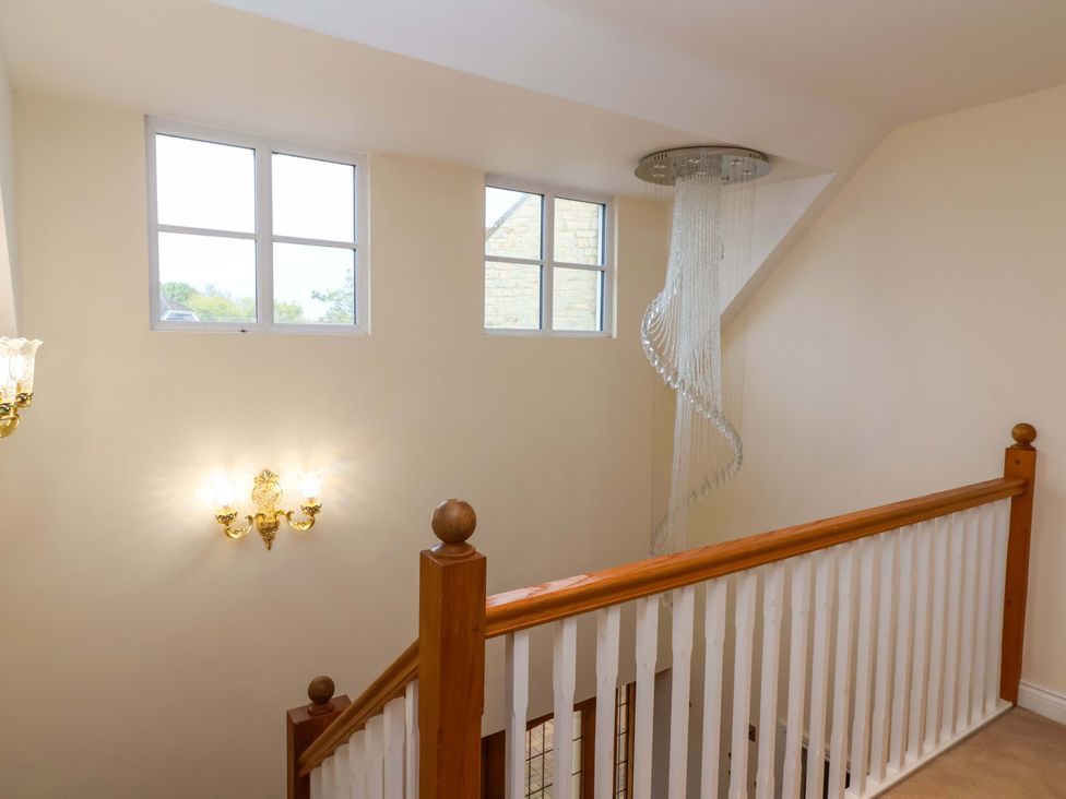 A staircase with windows and chandelier at The Mill House in Glastonbury