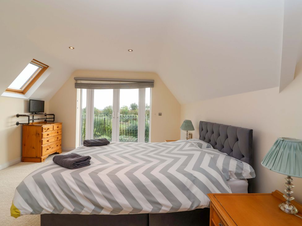 A bedroom with a bed, television, and drawers at The Mill House in Glastonbury