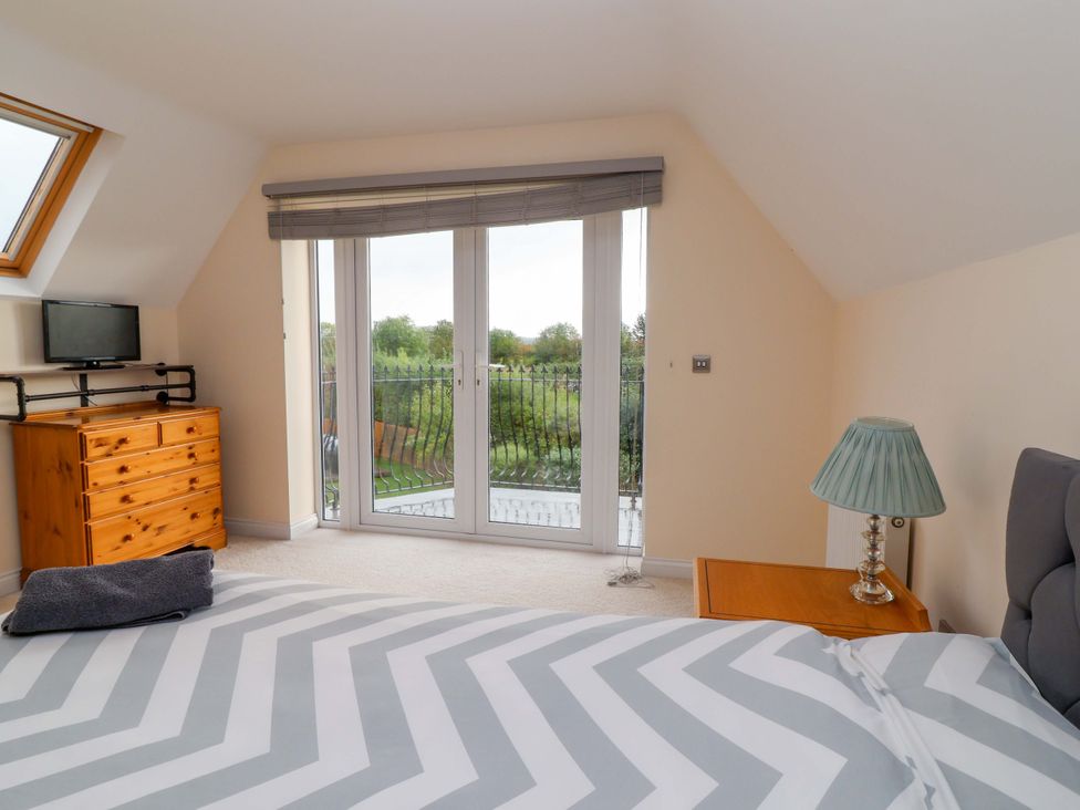 A bedroom with a bed and window doors leading outside at The Mill House in Glastonbury