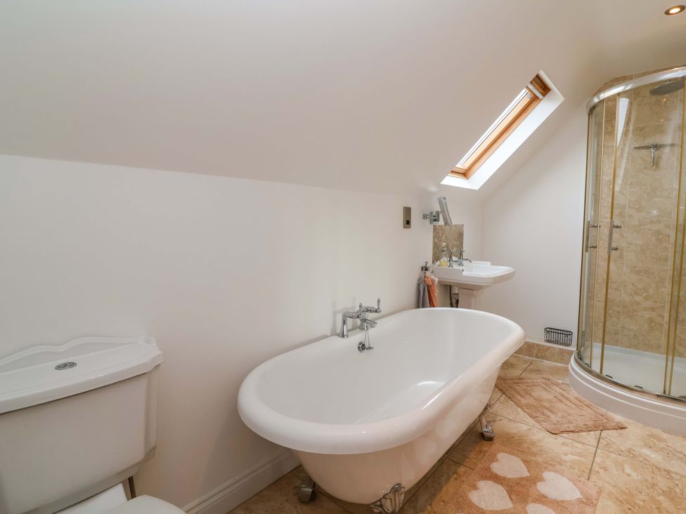 A bathroom with a bathtub, toilet, shower, and sink at The Mill House in Glastonbury