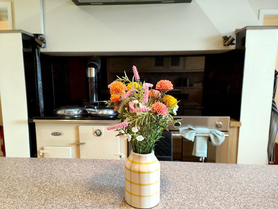A kitchen counter with flowers in a vase at Bush Nook House in Brampton