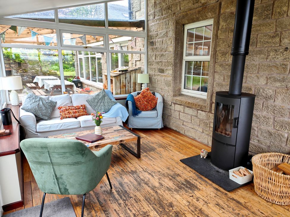 A conservatory with seating and a wood stove at Bush Nook House in Brampton