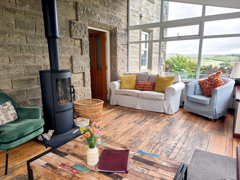 A conservatory with a wood stove and seating area at Bush Nook House in Brampton