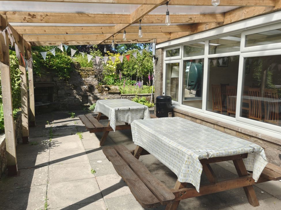 An outdoor dining area with tables and benches at Bush Nook House in Brampton, Cumbria
