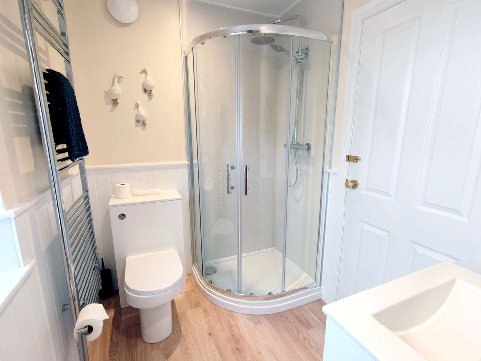 A bathroom featuring a shower, toilet, and towel radiator at Bush Nook House in Brampton, Cumbria