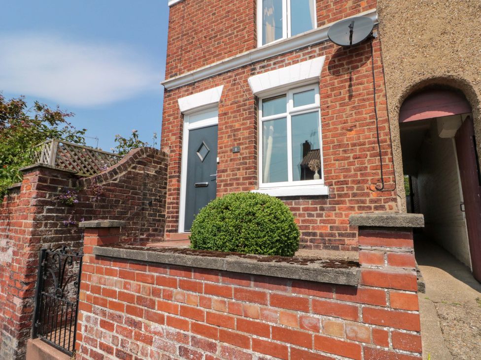 An outdoor view of a house with a door and windows at Moot Cottage in Driffield