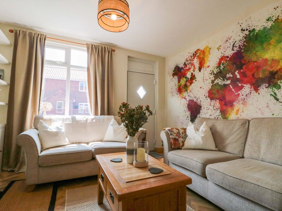 A living room with a couch, coffee table, and wall art at Moot Cottage in Driffield