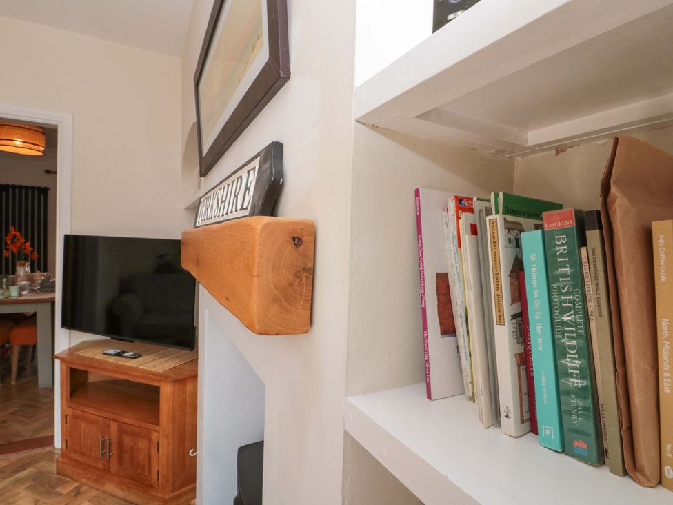 A living room with a bookshelf and television at Moot Cottage in Driffield