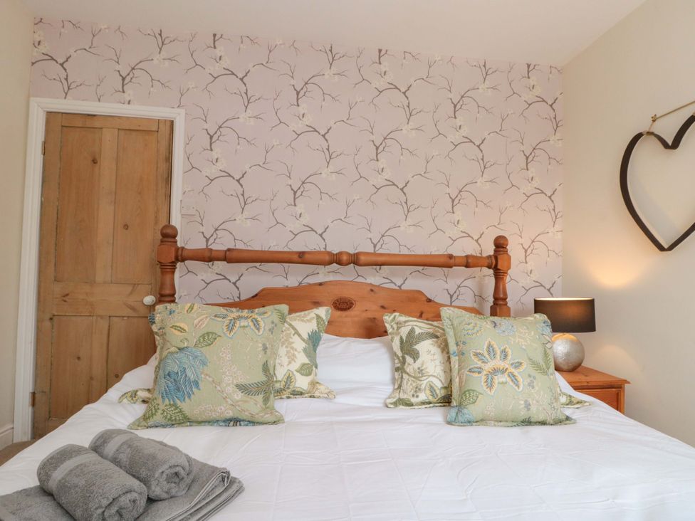 A bedroom with a bed and decorative pillows at Moot Cottage in Driffield