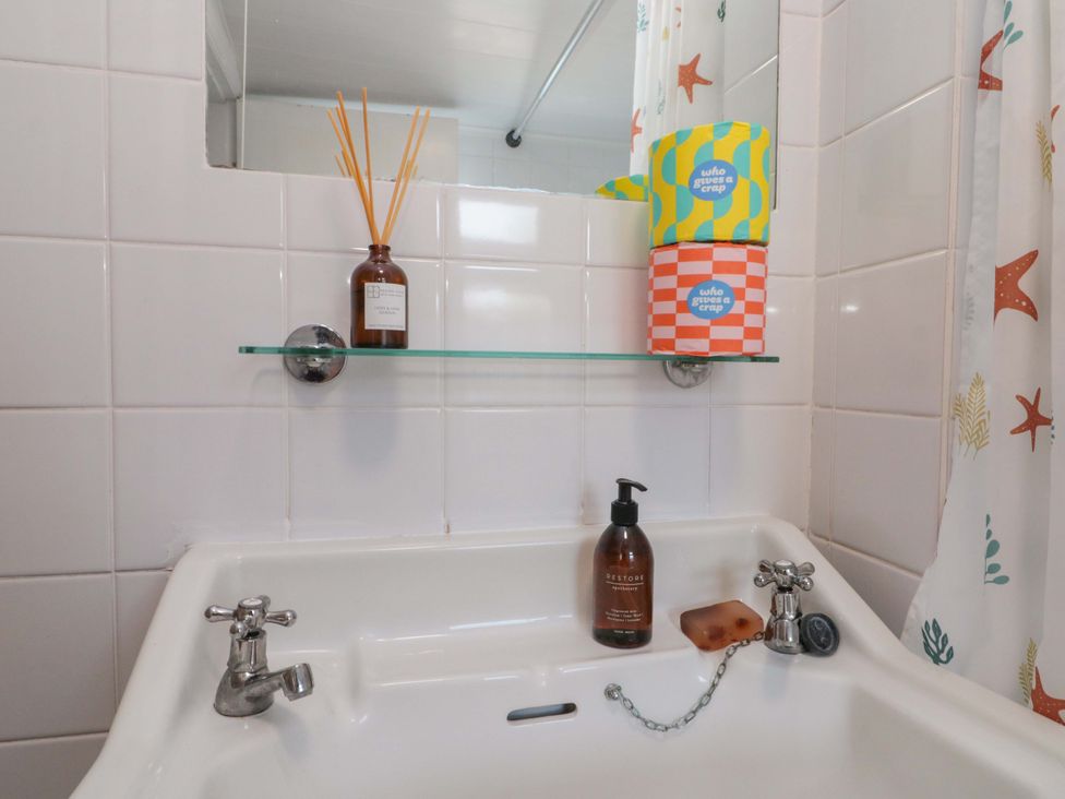 A sink and mirror with soap and decorative items at Moot Cottage in Driffield