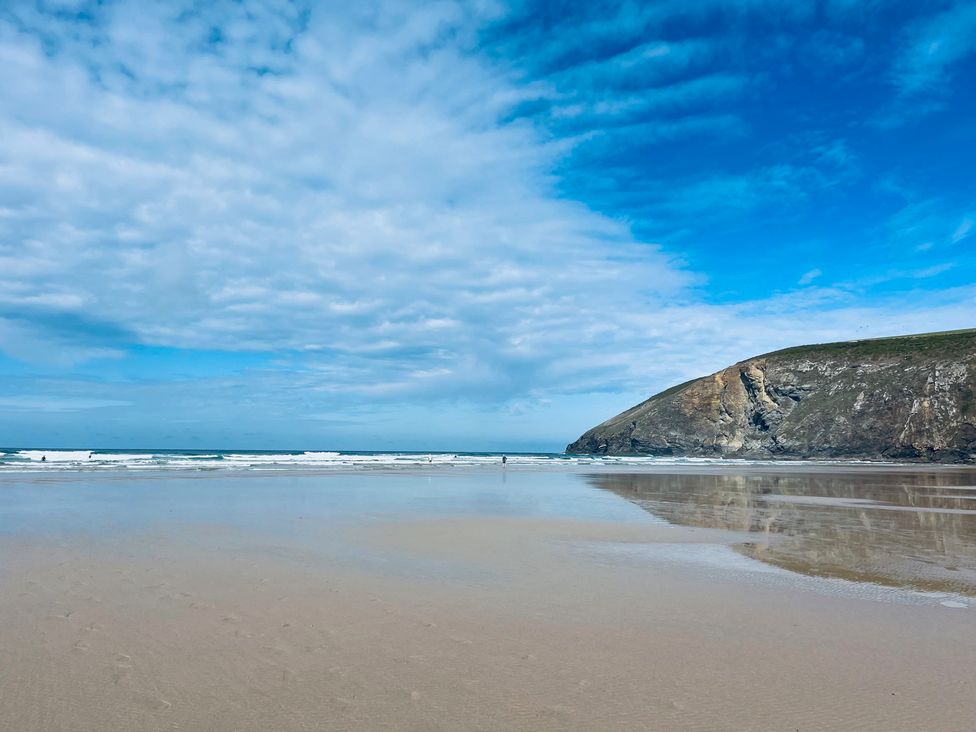 A beach with ocean waves and a cliff at Sunnybrae Cottage in Tintagel