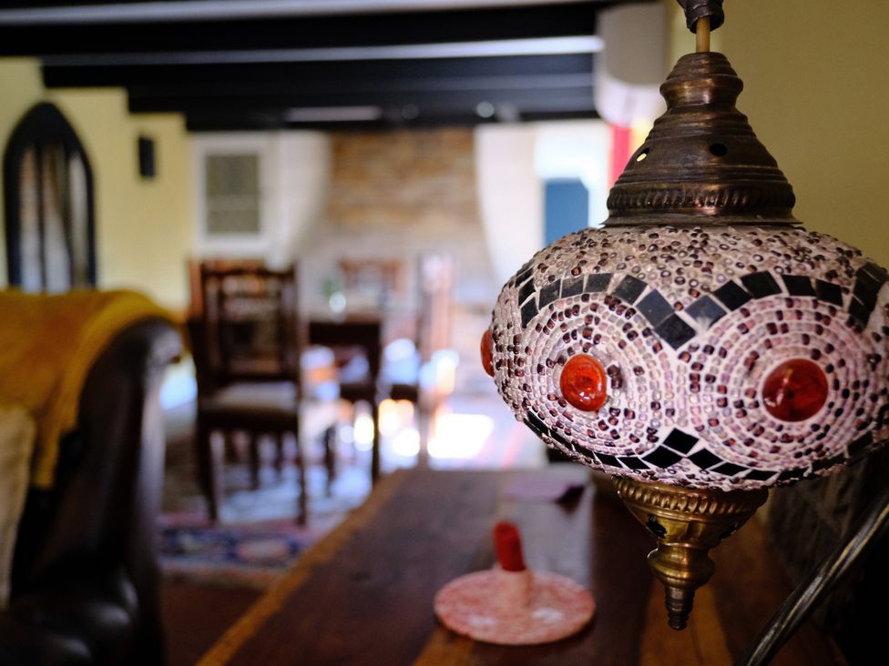 A dining room with a decorative lamp and wooden furniture at Sunnybrae Cottage in Tintagel