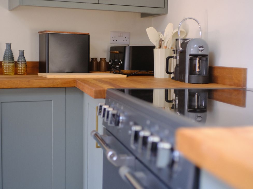 A kitchen with countertop, appliances and jars at Sunnybrae Cottage in Tintagel