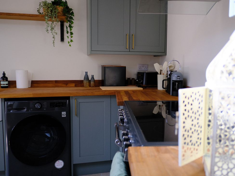 A kitchen with a washing machine and countertop appliances at Sunnybrae Cottage in Tintagel