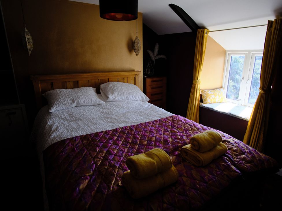 A bedroom with a bed and window at Sunnybrae Cottage in Tintagel