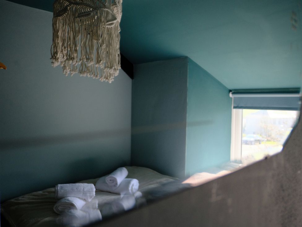 A bedroom with a bed and towels at Sunnybrae Cottage in Tintagel
