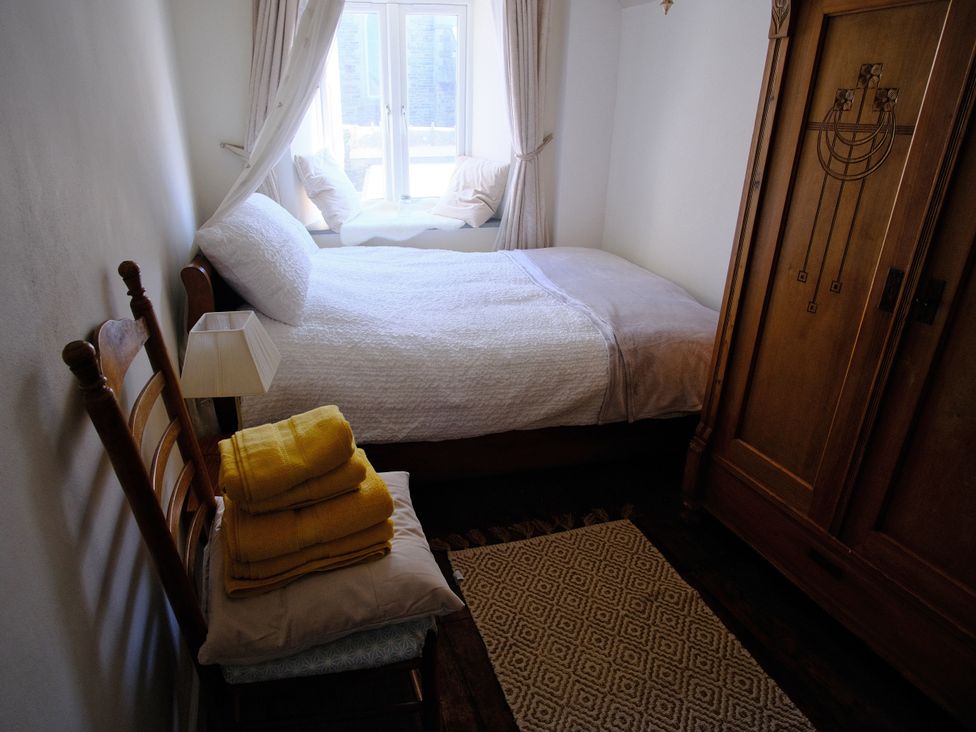 A bedroom with a bed and a window at Sunnybrae Cottage in Tintagel