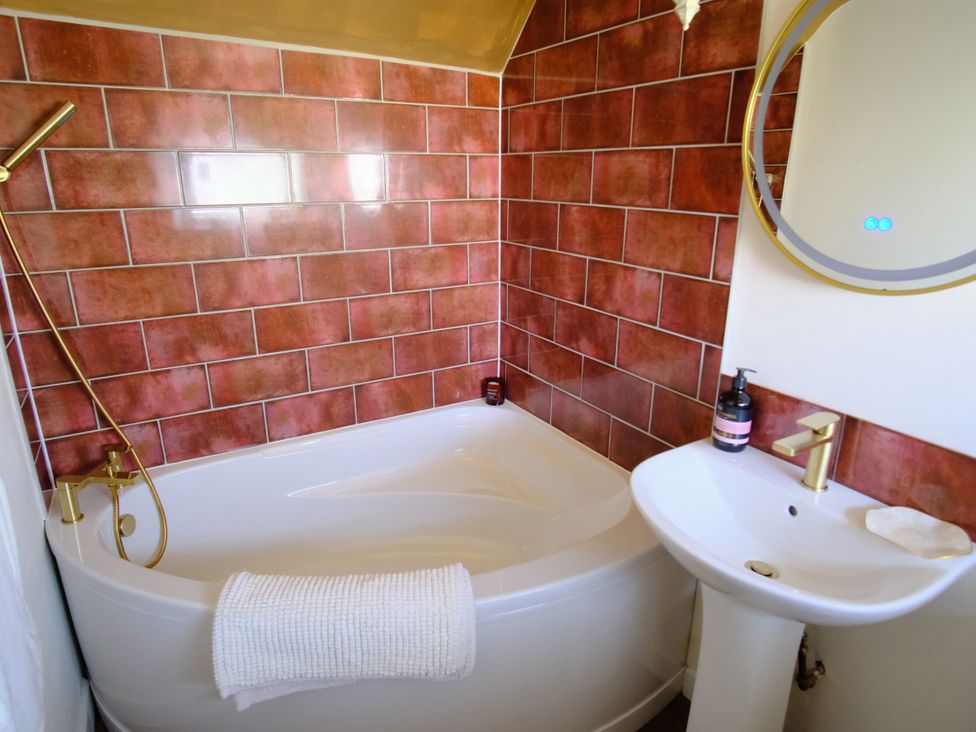 A bathroom with a bathtub and sink at Sunnybrae Cottage in Tintagel