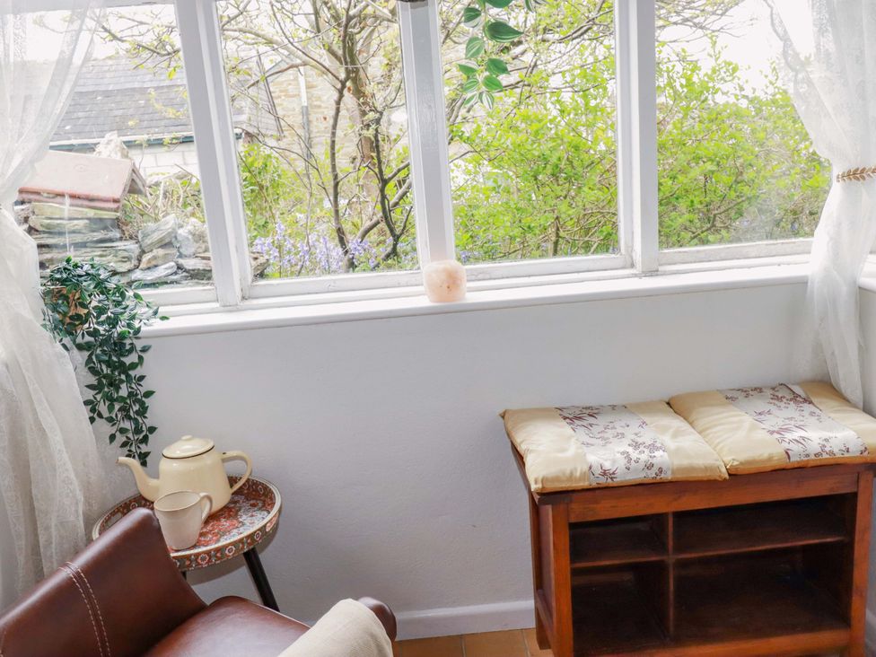 A snug with a window and a wooden bench at Sunnybrae Cottage in Tintagel
