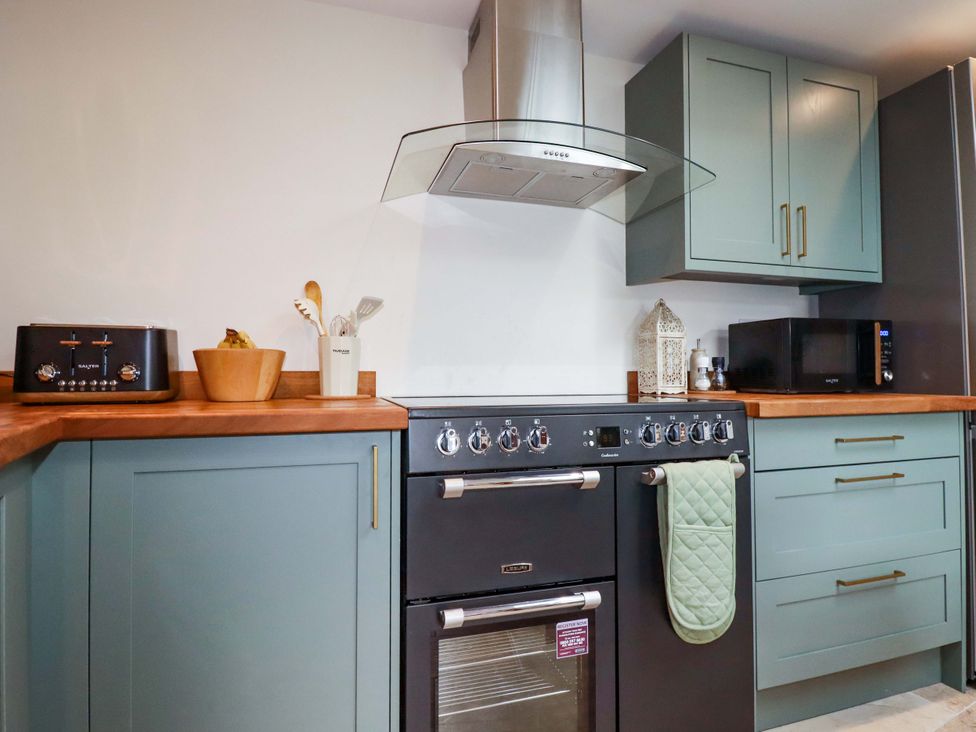 A kitchen with stove, microwave, and utensils at Sunnybrae Cottage in Tintagel