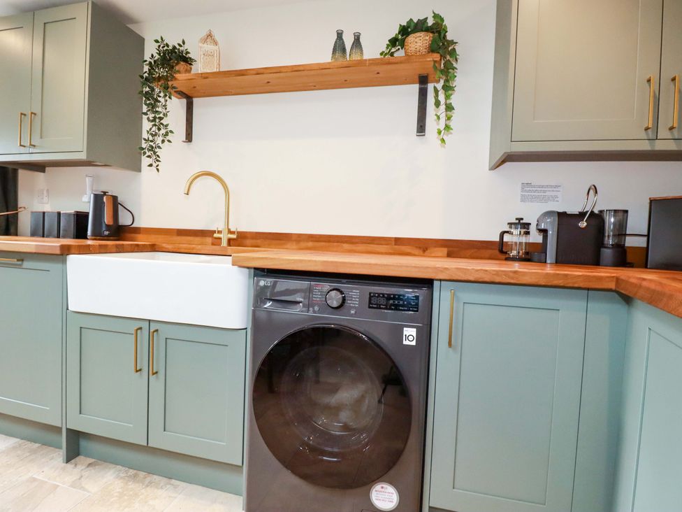 A kitchen with a sink and washing machine at Sunnybrae Cottage in Tintagel