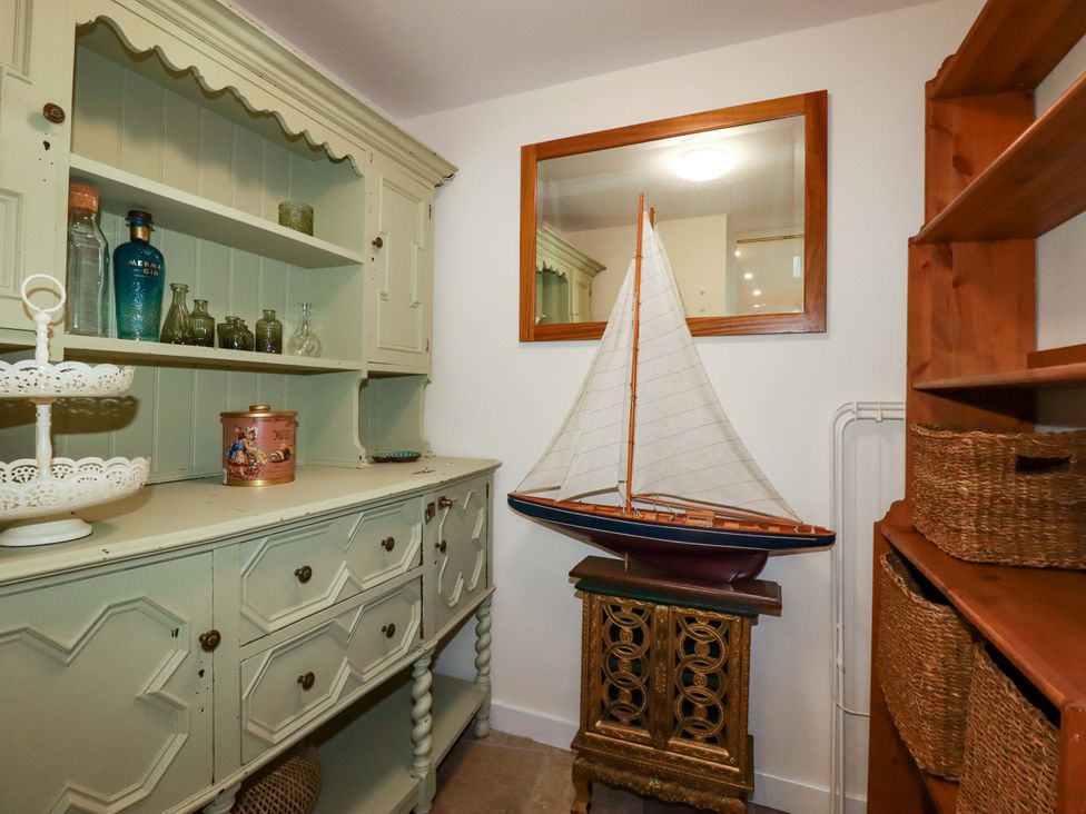 A cabinet and a sailing boat in a room at Sunnybrae Cottage in Tintagel