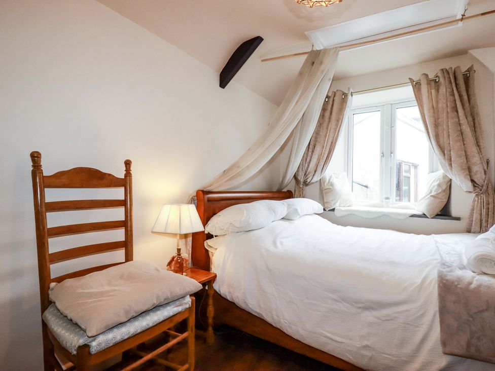 A bedroom with a bed and a chair at Sunnybrae Cottage in Tintagel