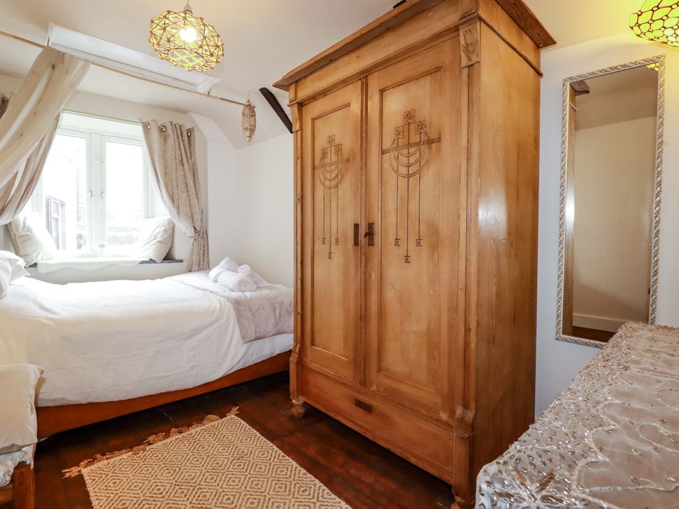 A bedroom with a bed and a wardrobe at Sunnybrae Cottage in Tintagel