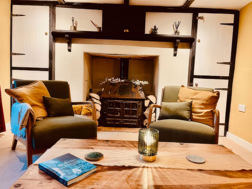 A living room with chairs, a table, and a fireplace at Sunnybrae Cottage in Tintagel