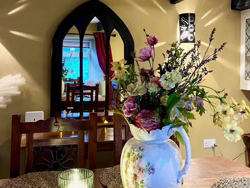 A dining room with flowers on a table at Sunnybrae Cottage Tintagel