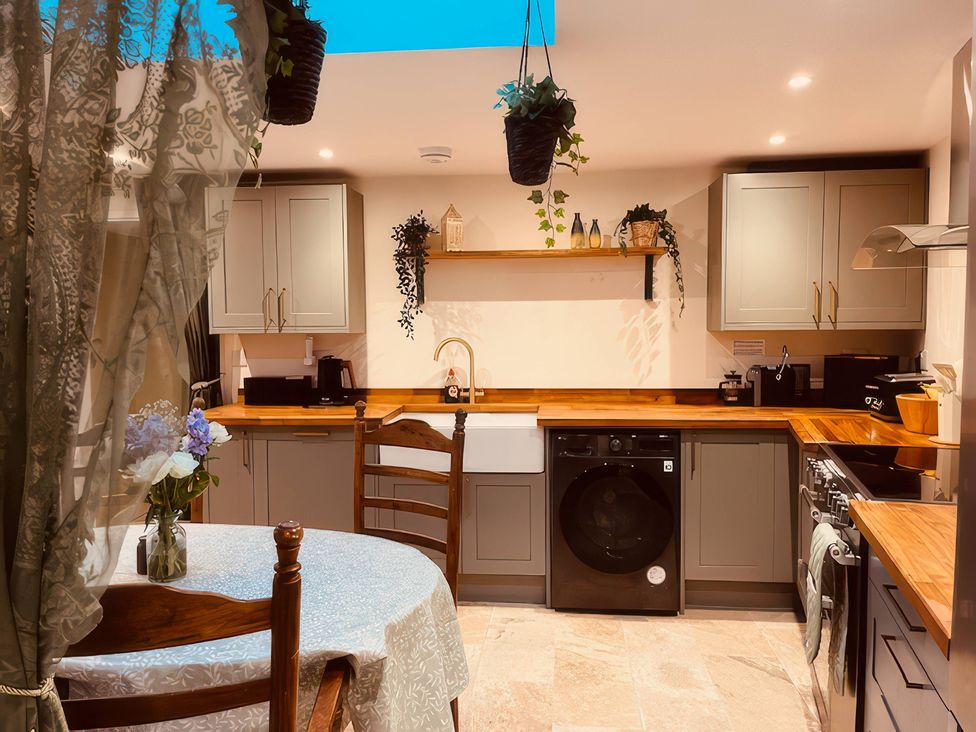A kitchen with a table and sink at Sunnybrae Cottage in Tintagel
