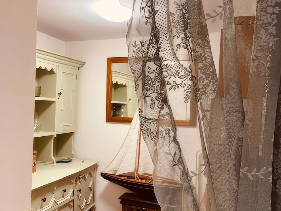 An indoor room with a curtain and furniture at Sunnybrae Cottage Tintagel