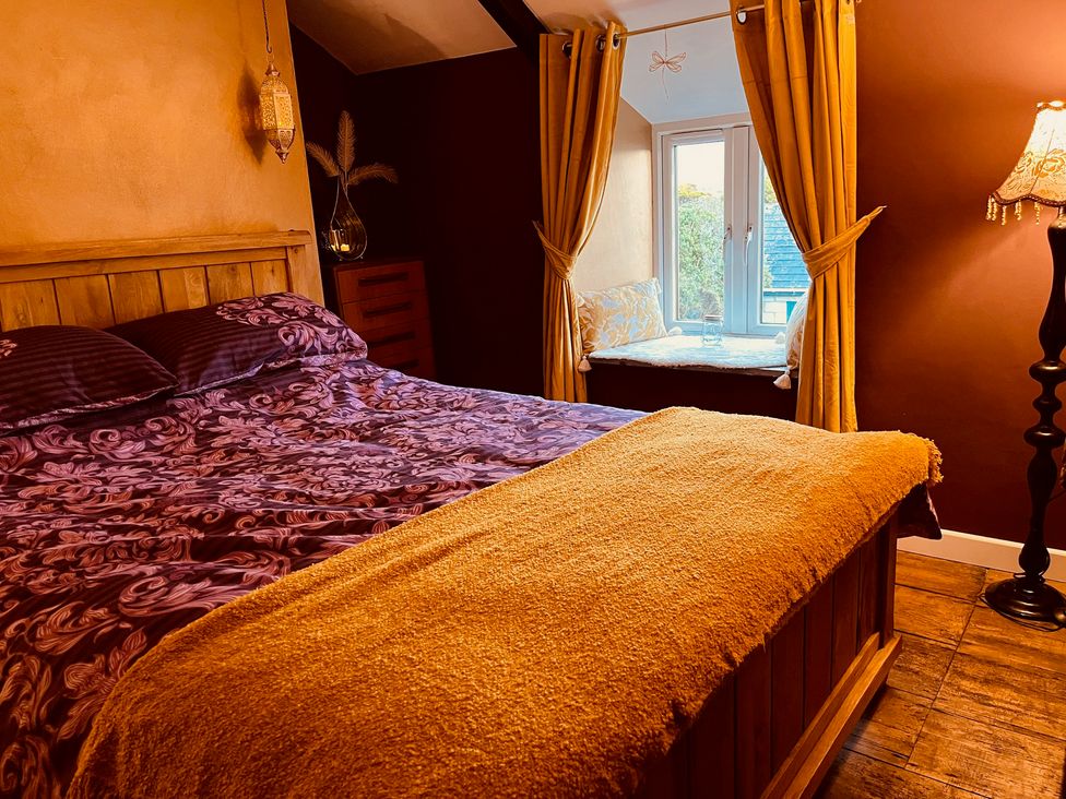 A bedroom with a bed and a window seat at Sunnybrae Cottage in Tintagel