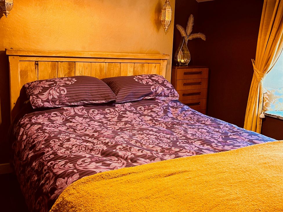 A bedroom with a wooden bed and bedside table at Sunnybrae Cottage in Tintagel
