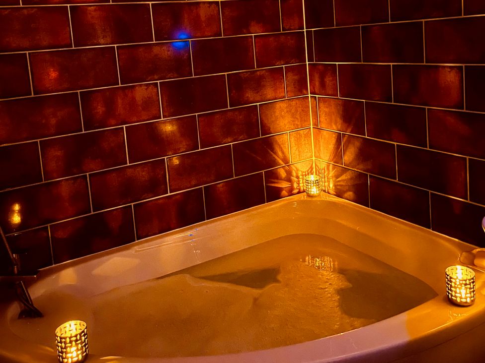A bathtub with water and candles at Sunnybrae Cottage in Tintagel