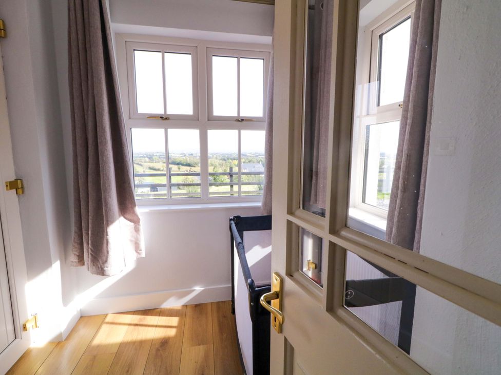 A bedroom with a crib and windows at Molly's Cottage in Enniskillen