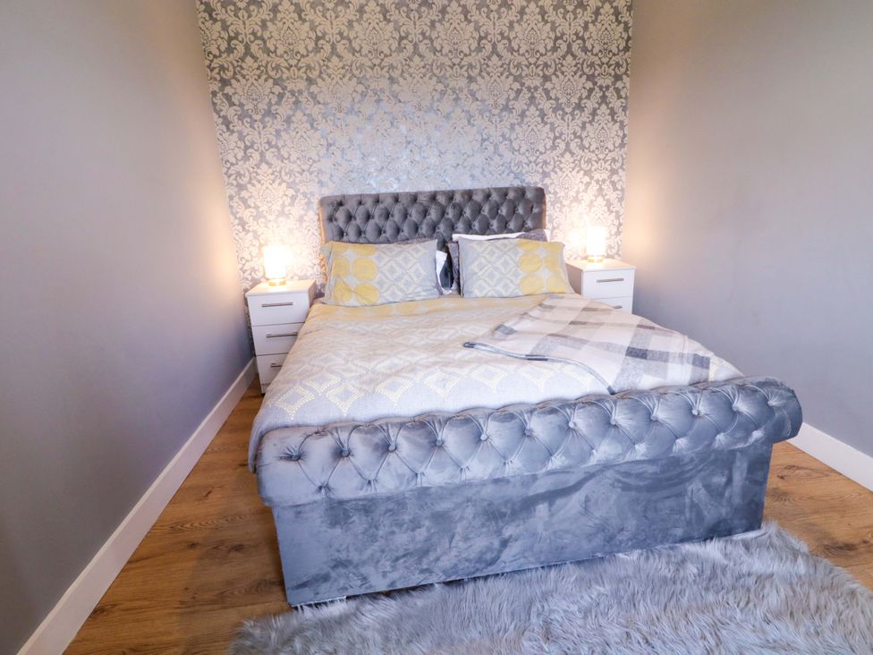 A bedroom with a bed and nightstands at Molly's Cottage Enniskillen