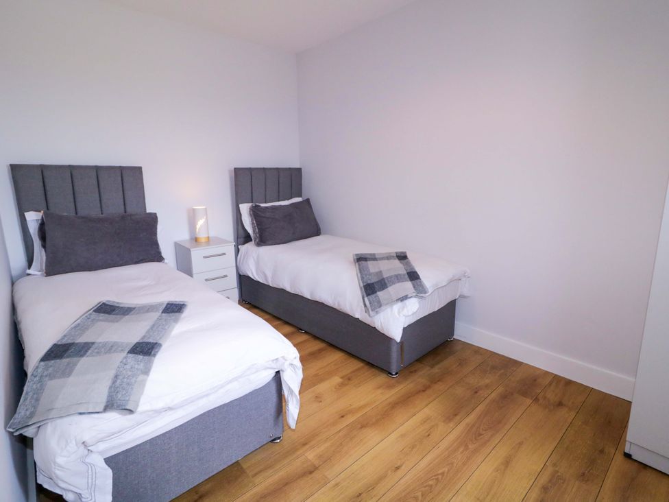 A bedroom with two beds and a nightstand at Molly's Cottage in Enniskillen