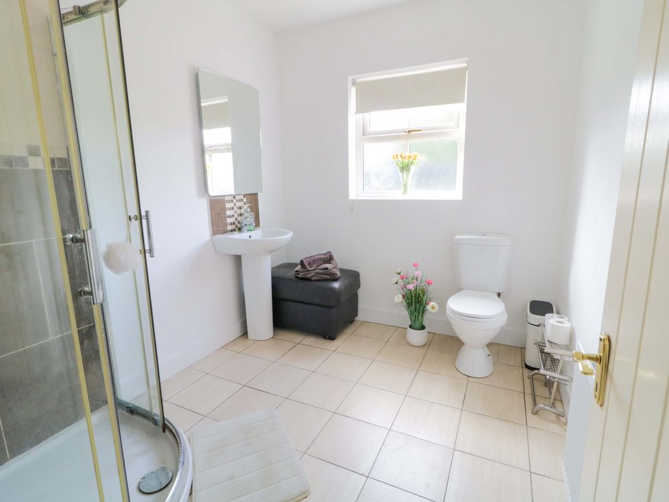 A bathroom with a shower, toilet, sink and flowers at Molly's Cottage Enniskillen
