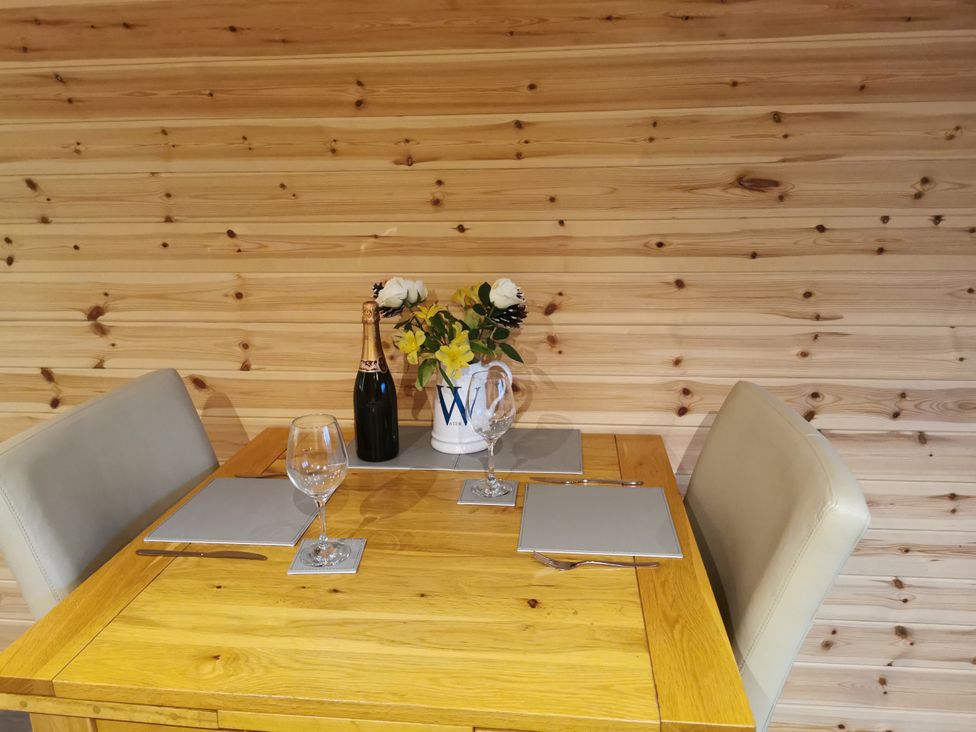 A dining room table set with glasses and flowers at Lodge 1 Pontyates