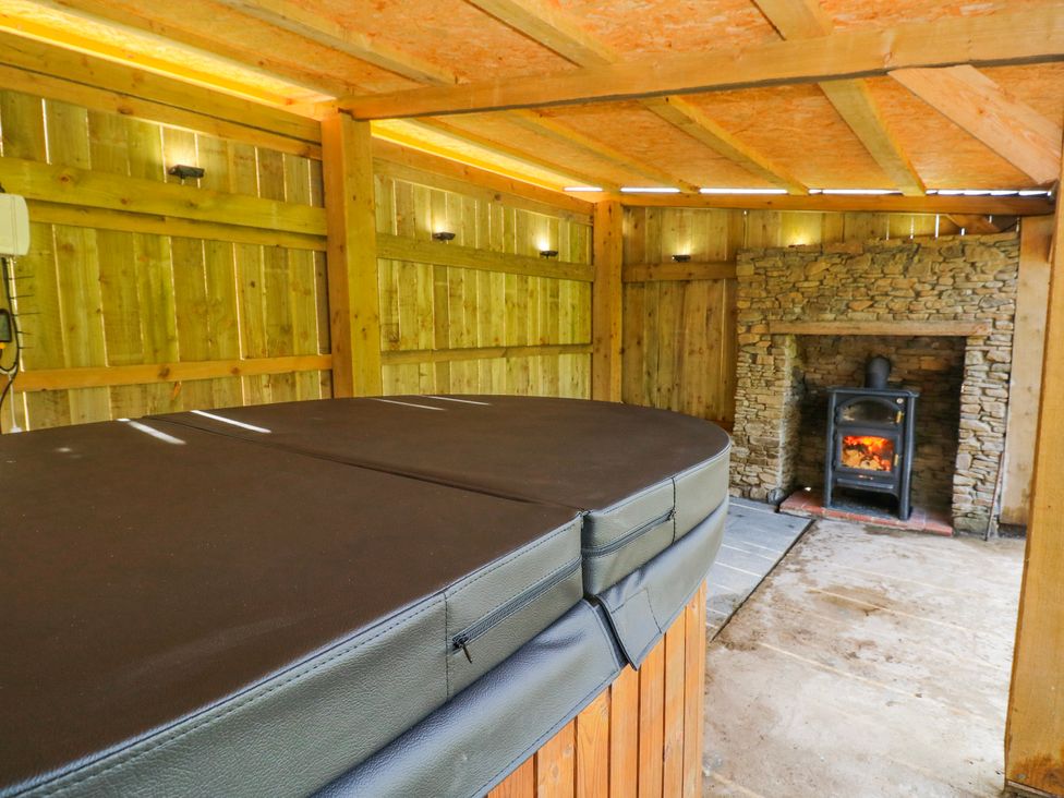 A hot tub with a stone fireplace at Lodge 1 near Pontyates