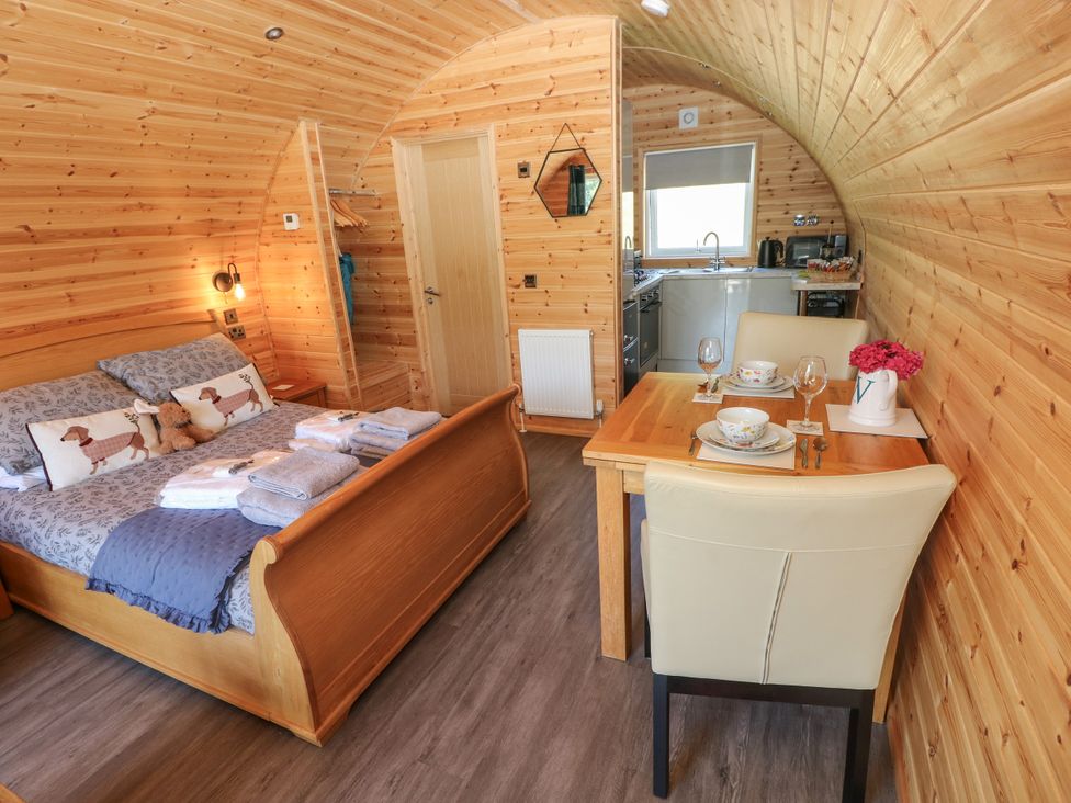 A bedroom with a bed and dining area at Thelma’s Lodge near Pontyates