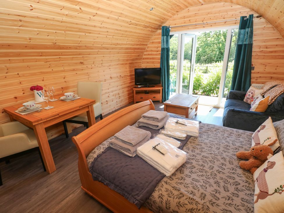 A studio with a bed, sofa, dining table, and television at Thelma’s Lodge near Pontyates