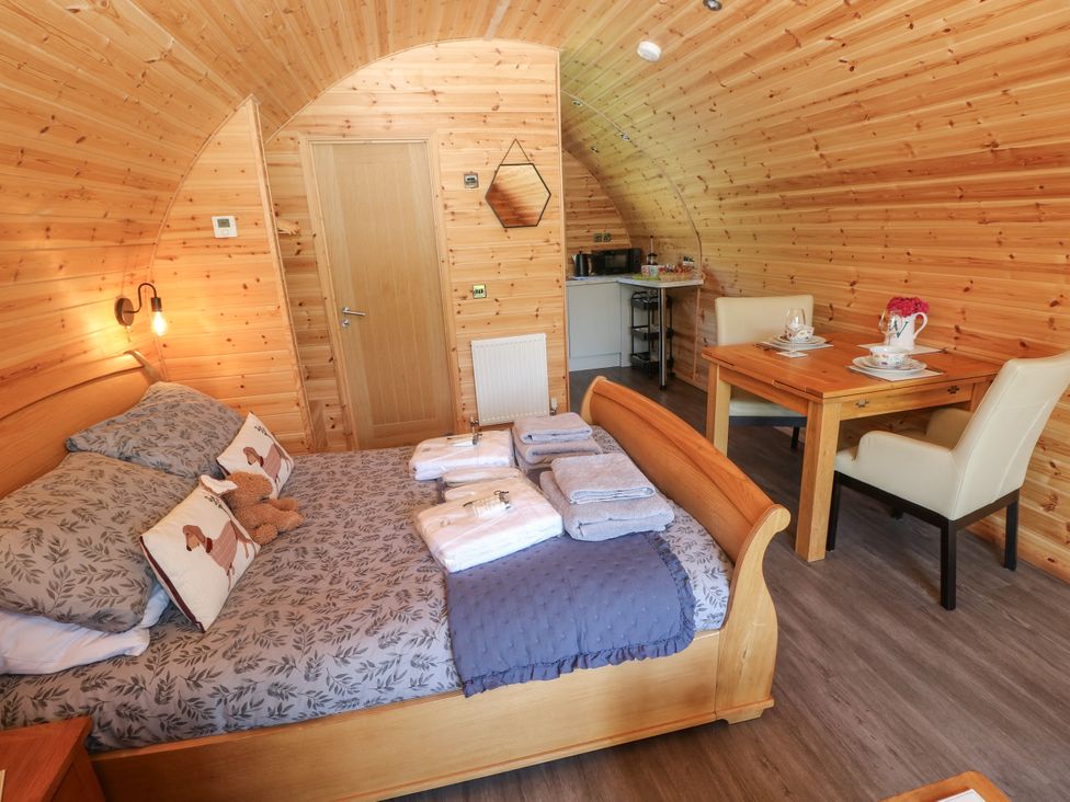 A bedroom with a bed and kitchenette at Thelma’s Lodge near Pontyates