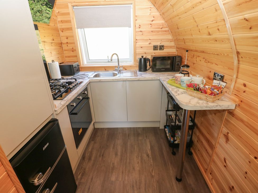 A kitchen with stove, sink, and refrigerator at Thelma’s Lodge near Pontyates