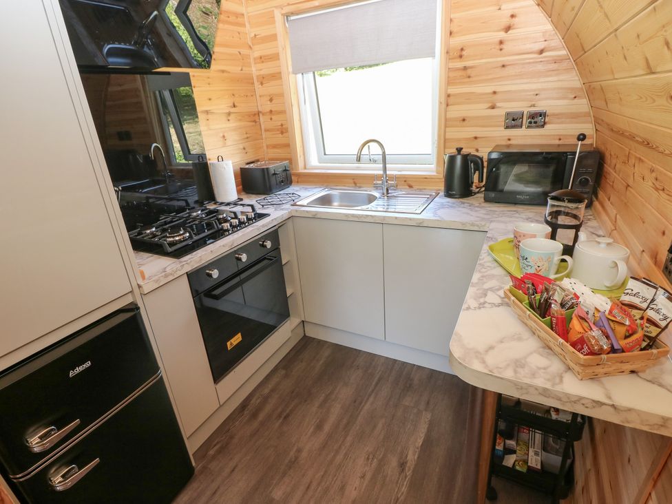 A kitchen with sink, gas stove, refrigerator, and snacks at Thelma’s Lodge near Pontyates