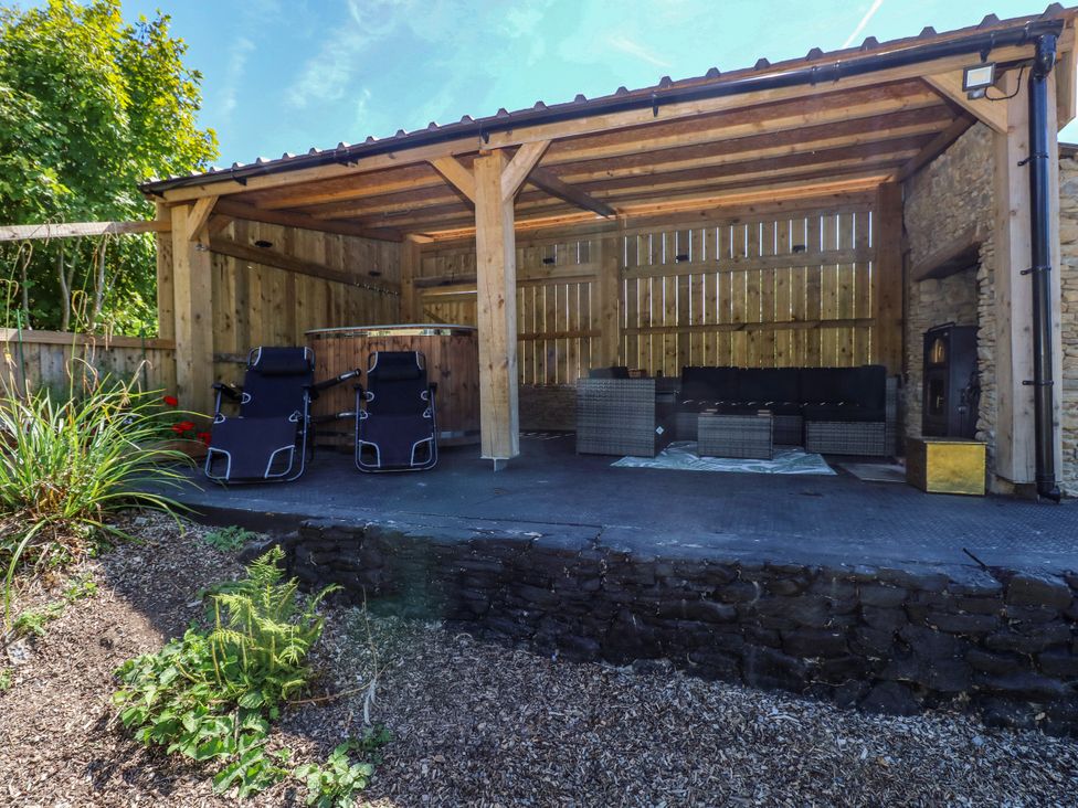 An outdoor seating area with garden furniture and a canopy at Thelma’s Lodge near Pontyates