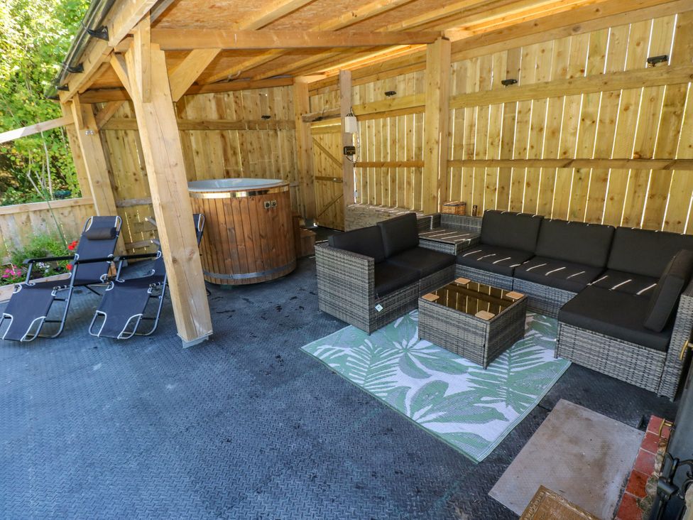 An outdoor seating area with a hot tub and lounge furniture at Thelma’s Lodge near Pontyates